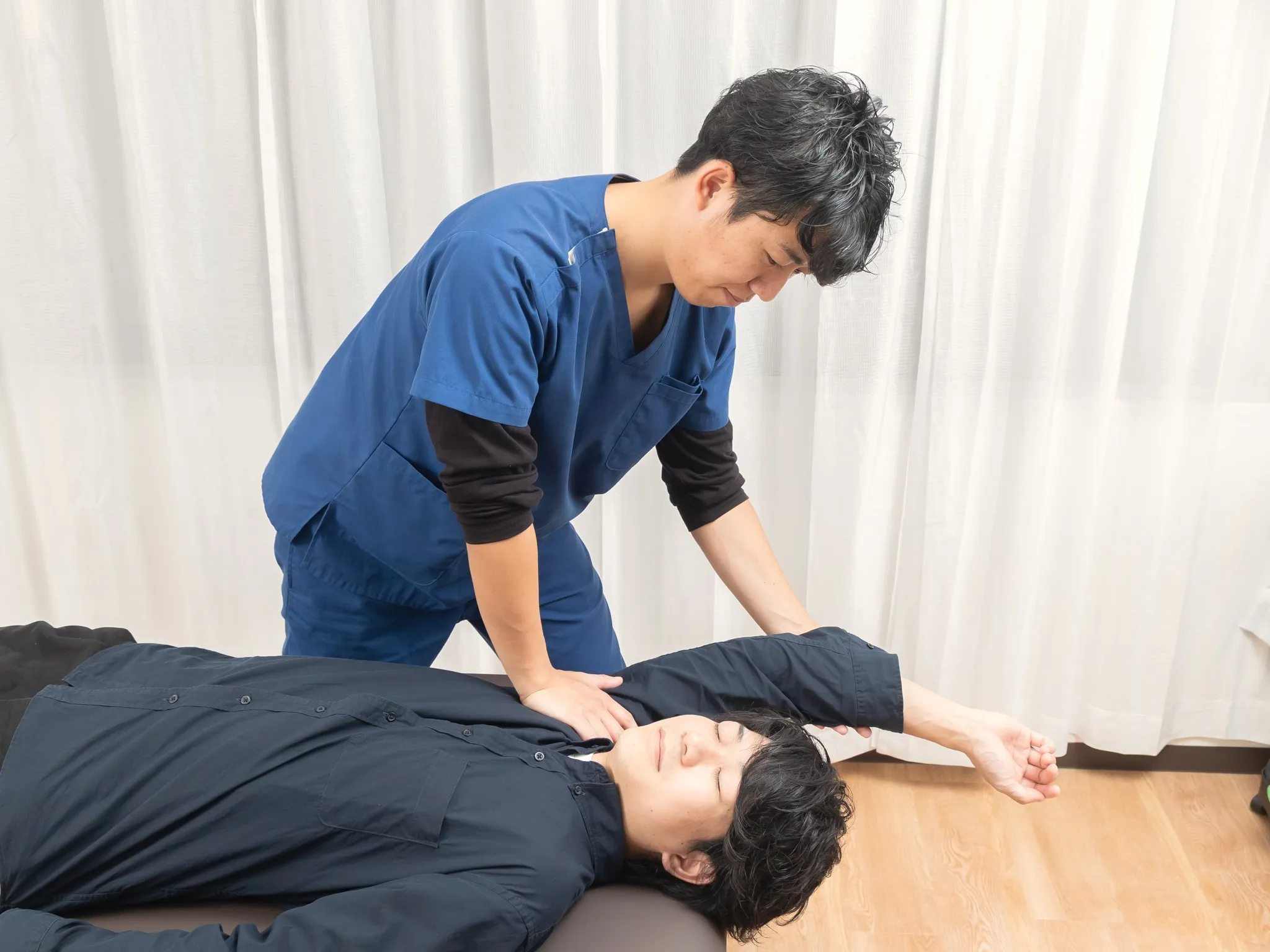 施術者が、仰向けに寝た方の胸の上に手を当てている様子